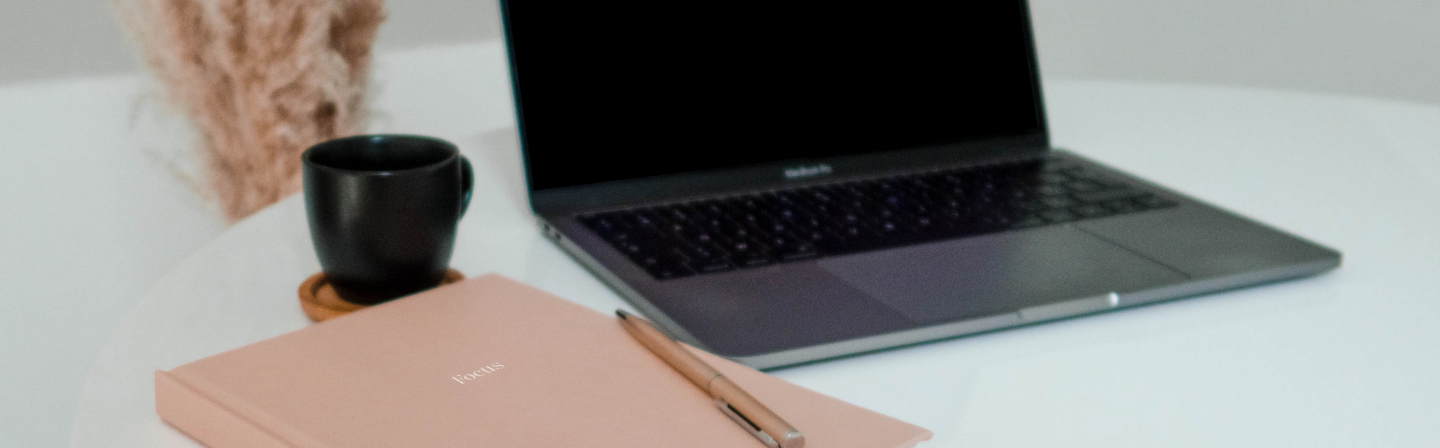 Laptop y cuaderno de notas con un lápiz y una taza.